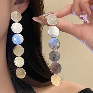 Detail view of long silver dangling earrings with six brushed circular metal discs.