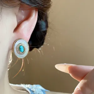Macro view showing vintage oval stud earring with mother of pearl and turquoise