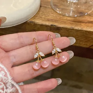 Detail view of dainty pink cherry earrings with cat's eye stones and zircon leaves