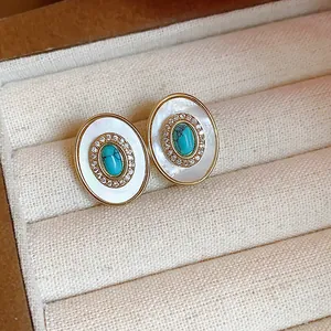 Close-up detail of vintage oval earrings with turquoise, zircon and mother-of-pearl inlay