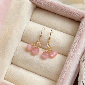 Close-up of pink cherry cat's eye earrings with sparkling zircon leaves in a gift box