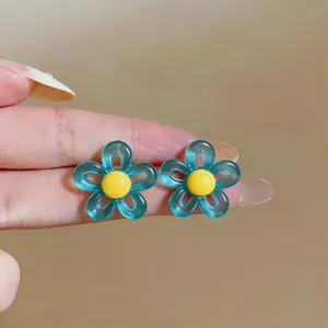 Gros plan détaillé de boucles d'oreilles fleurs en résine bleu sarcelle et jaune