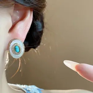 Close-up detail of vintage oval stud earring with turquoise and mother-of-pearl