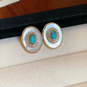 Close-up detail of oval vintage earrings with mother of pearl and turquoise