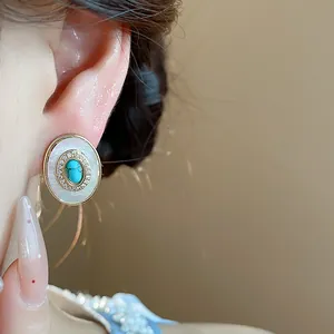 Macro view of vintage oval mother-of-pearl earring with turquoise and zircon inlay