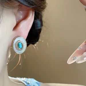 Detailed view of an oval mother-of-pearl stud earring with a turquoise center stone.