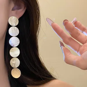 Detailed macro view of long silver metallic earrings featuring stacked circular discs.
