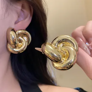 Detalle de los pendientes de botón vintage con diseño de flor retorcida dorada