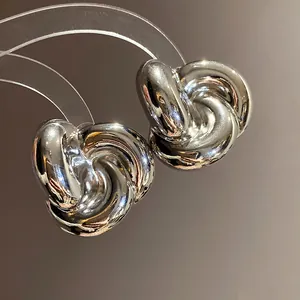 Vista macro de elegantes pendientes de botón con diseño de nudo de flor plateada