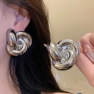 Primer plano de elegantes pendientes de flor retorcida plateados para un look de moda retro.