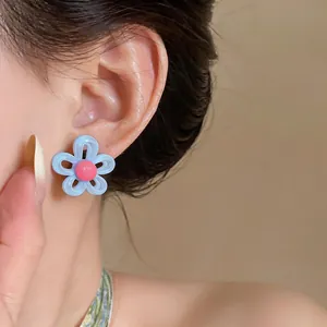 Gros plan d'une boucle d'oreille fleur bleue et rose portée sur l'oreille d'un mannequin