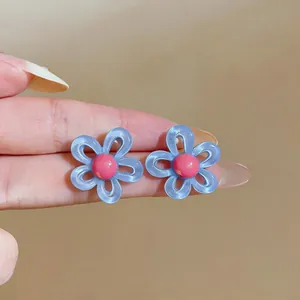 Gros plan détaillé des boucles d'oreilles fleurs bleu et rose au style dopamine vibrant