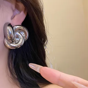Primer plano de pendientes de plata vintage con forma de flor retorcida en el modelo