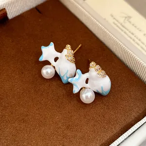 Close-up of zircon enamel pearl fish-shaped stud earrings displayed in a luxury gift box