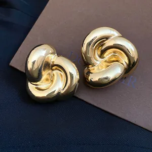 Vista macro de pendientes de botón vintage de flor retorcida dorada con acabado pulido brillante