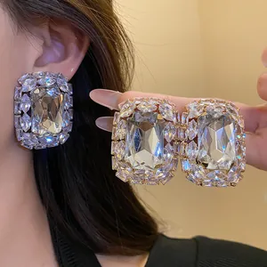Detailed close-up of luxurious square silver needle earrings with shimmering diamonds