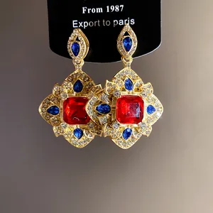 Macro view of vintage palace style earrings with red and blue stones in gold finish