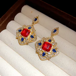 Detailed view of vintage court-style gold earrings with red and blue stones