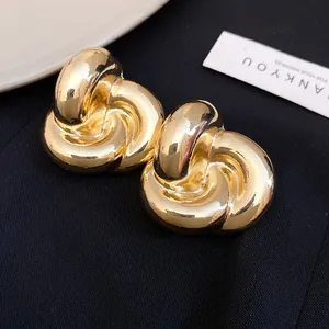 Primer plano de elegantes pendientes de botón con nudo dorado sobre fondo negro
