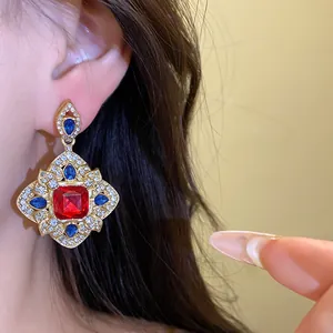 Close-up of vintage royal style rhombus drop earring with red and blue crystals.