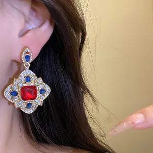 Detailed view of vintage court style rhombic earrings with red and blue crystals.