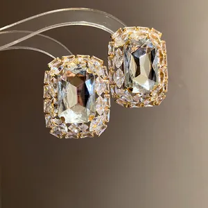 Close-up of elegant gold-toned rectangular stud earrings with clear sparkling stones