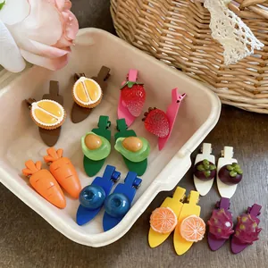 Gros plan de barrettes à cheveux aux motifs de fruits : fraise, avocat et orange