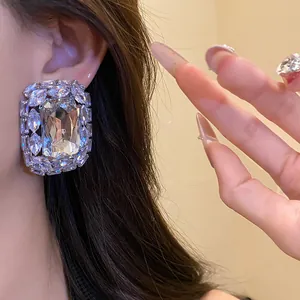 Close-up of a luxury square rhinestone stud earring showing elegant wearing effect.