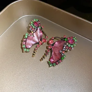 Macro detail view of vintage butterfly earrings with pink resin and sparkling rhinestones