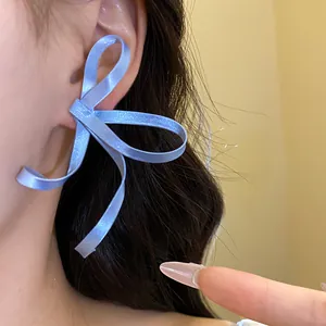 Primo piano di grandi orecchini a fiocco in raso azzurro per donna