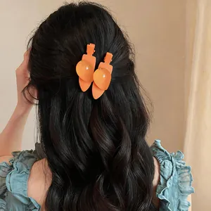 Vue détaillée de jolies pinces à cheveux en forme de fruits orange sur cheveux sombres