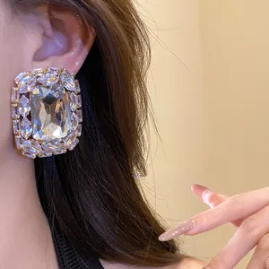 Close-up detail of luxury oversized square crystal stud earrings with silver needle