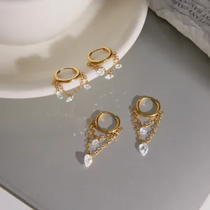 Nahaufnahme von goldenen Edelstahl-Creolen mit funkelnden Zirkon-Quasten.