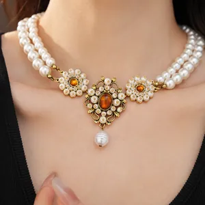 Close-up of a vintage double-layer pearl necklace with ornate amber stone pendant detail.