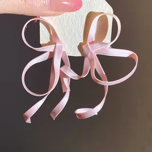 Primo piano di orecchini a fiocco in nastro di raso rosa che mostrano la delicata trama del tessuto