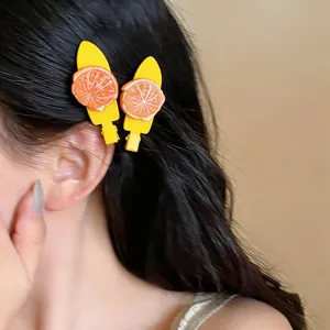 Détail de barrettes à fruits avec tranches d'orange portées sur le côté des cheveux