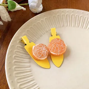Gros plan de barrettes à cheveux en forme d'orange avec texture d'agrume réaliste.