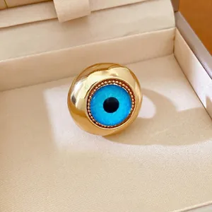 Audace anello placcato oro con occhio del male in resina blu in un portagioie elegante