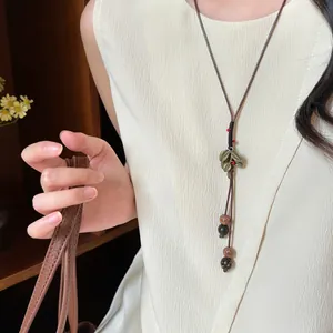 Detailed shot of a New Chinese style wood bead necklace with leaf charms on a model