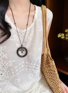Detail of vintage Oriental style necklace with wooden ring pendant and leaf charm.
