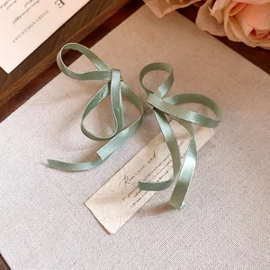 Primo piano dettagliato di eleganti orecchini a fiocco in nastro di seta verde vintage