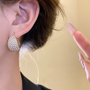 Detailaufnahme eleganter Vintage-Creolen mit Perlen und Strass am Ohr eines Models