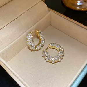 Nahaufnahme von Vintage-Creolen mit eleganten Perlen und funkelnden Strasssteinen in Goldoptik.