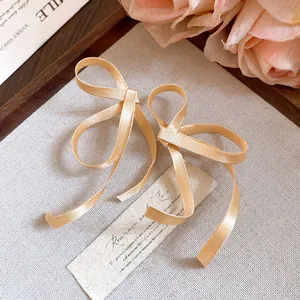 Primo piano dettagliato di orecchini a fiocco in nastro di seta champagne dall'aspetto elegante