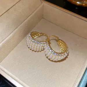 Detailansicht von Retro-Gold-Creolen mit weißen Perlen und glitzernden Straßsteinen
