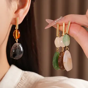 Pendientes colgantes retro de resina geométrica con pernos dorados en una modelo asiática