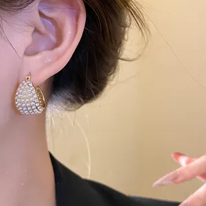 Nahaufnahme von Vintage Gold-Creolen mit weißen Perlen und funkelnden Strasssteinen