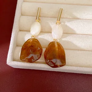 Pendientes vintage de resina ámbar y perlas blancas en una bandeja de joyería crema