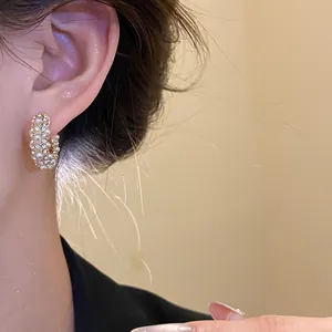 Detailansicht eines goldenen Retro-Ohrrings mit eleganten Perlen und glitzernden Kristallen