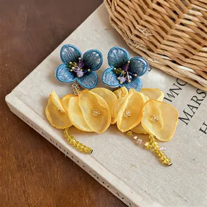Close-up of handmade blue fabric flower and yellow chiffon petal tassel earrings.